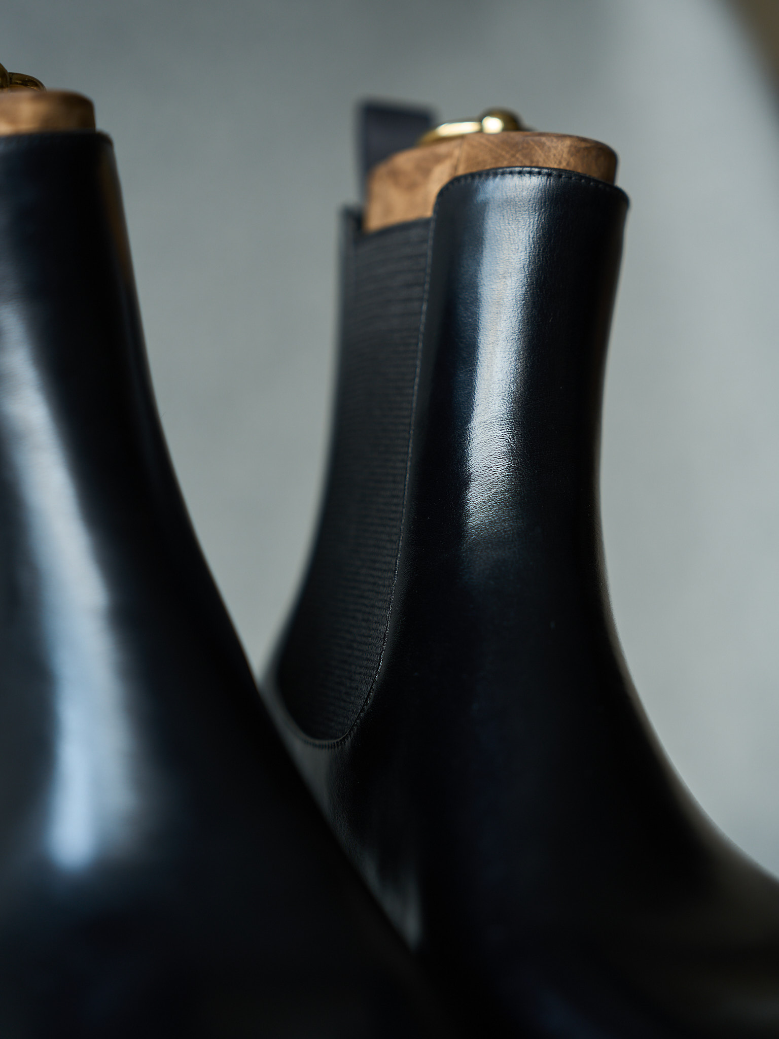 Black leather ankle boots with wooden heel detail and gold accent.