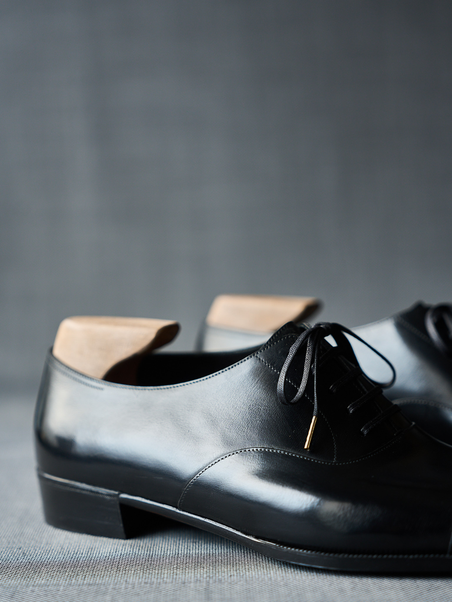 Black leather dress shoes with gold lace detail and open-back design.