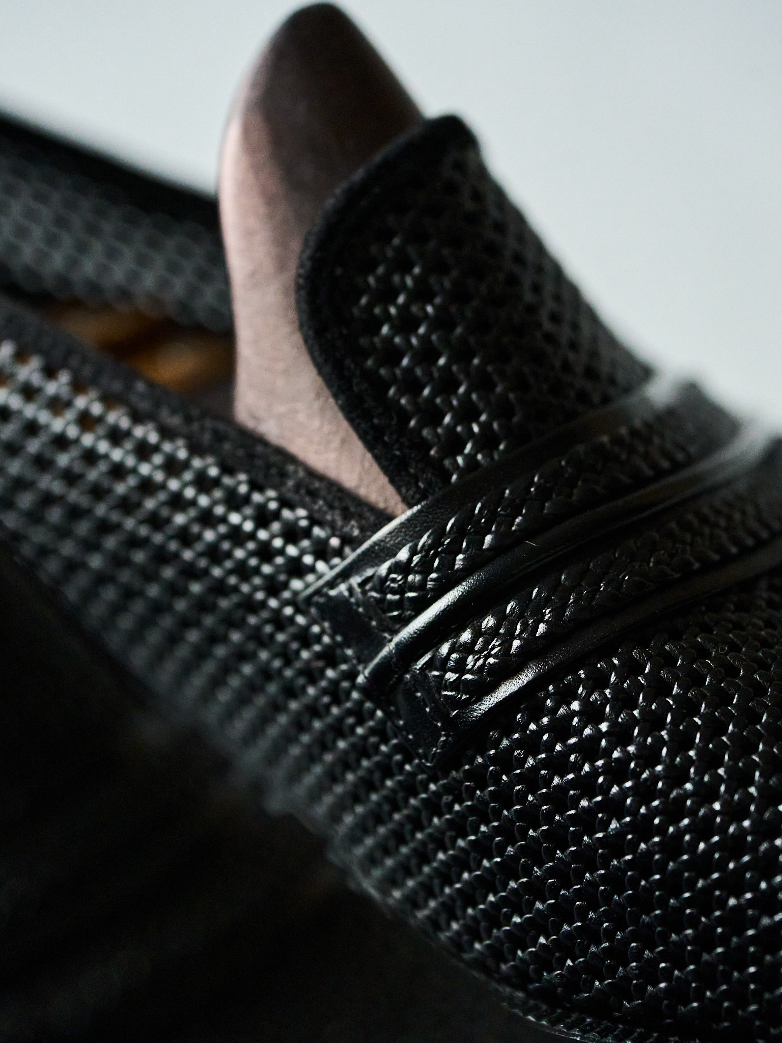 Black woven leather loafer with sleek design and textured slip-on comfort.