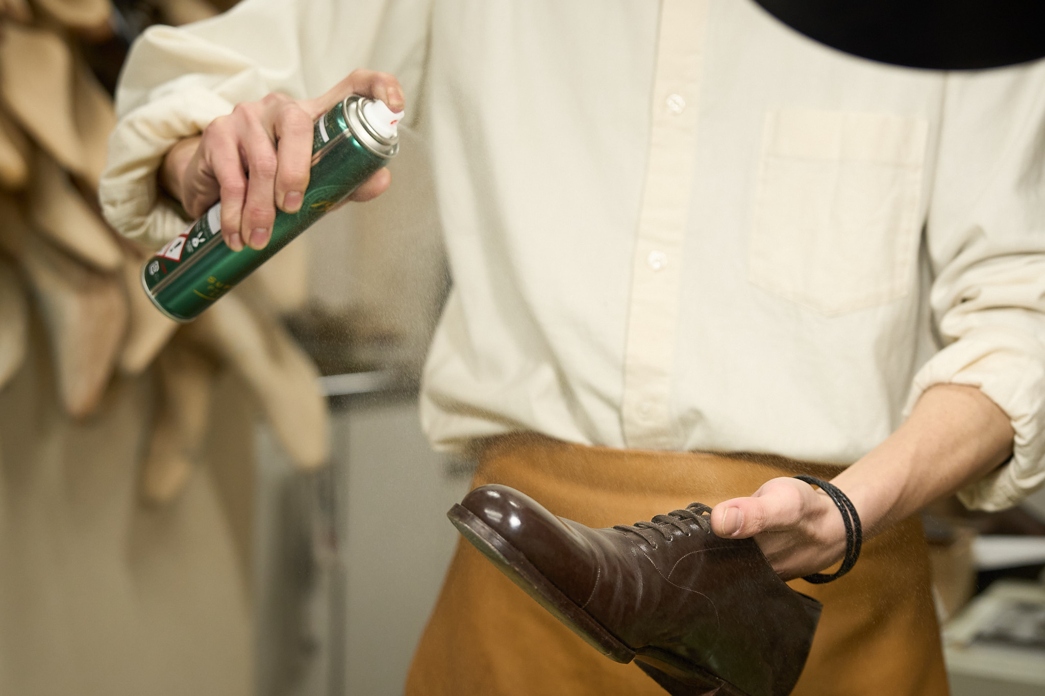Applying waterproof spray to a leather shoe