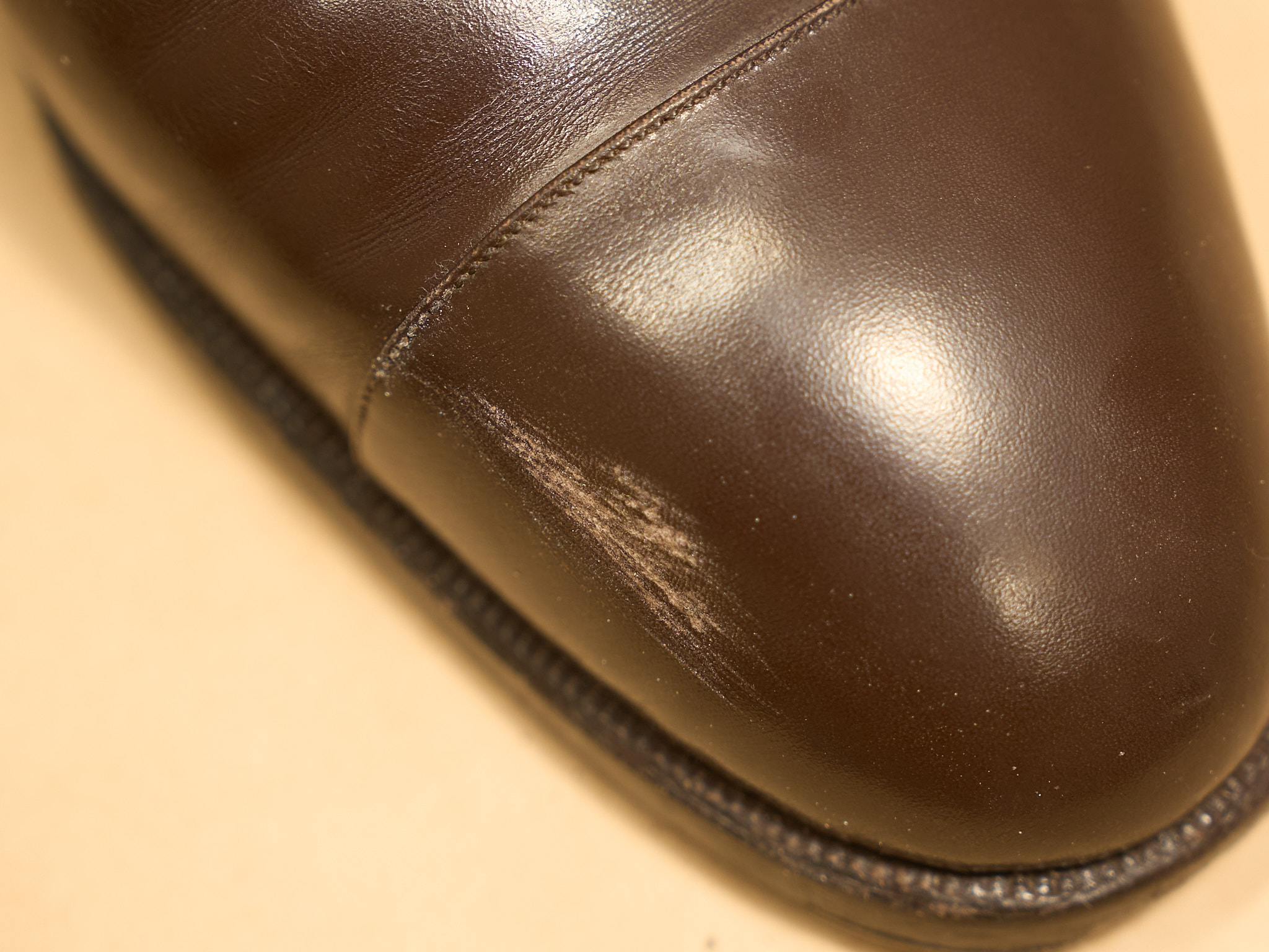 Brown leather shoe with a shallow scratch on the toe