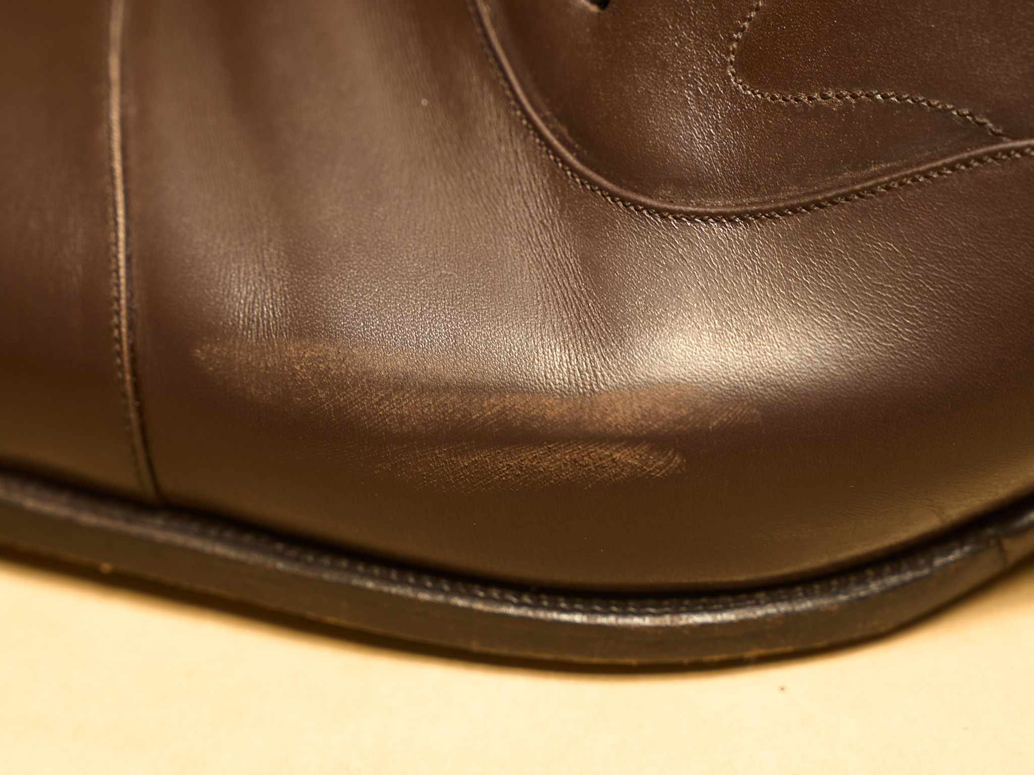 Brown leather shoe with a surface scuff on the toe