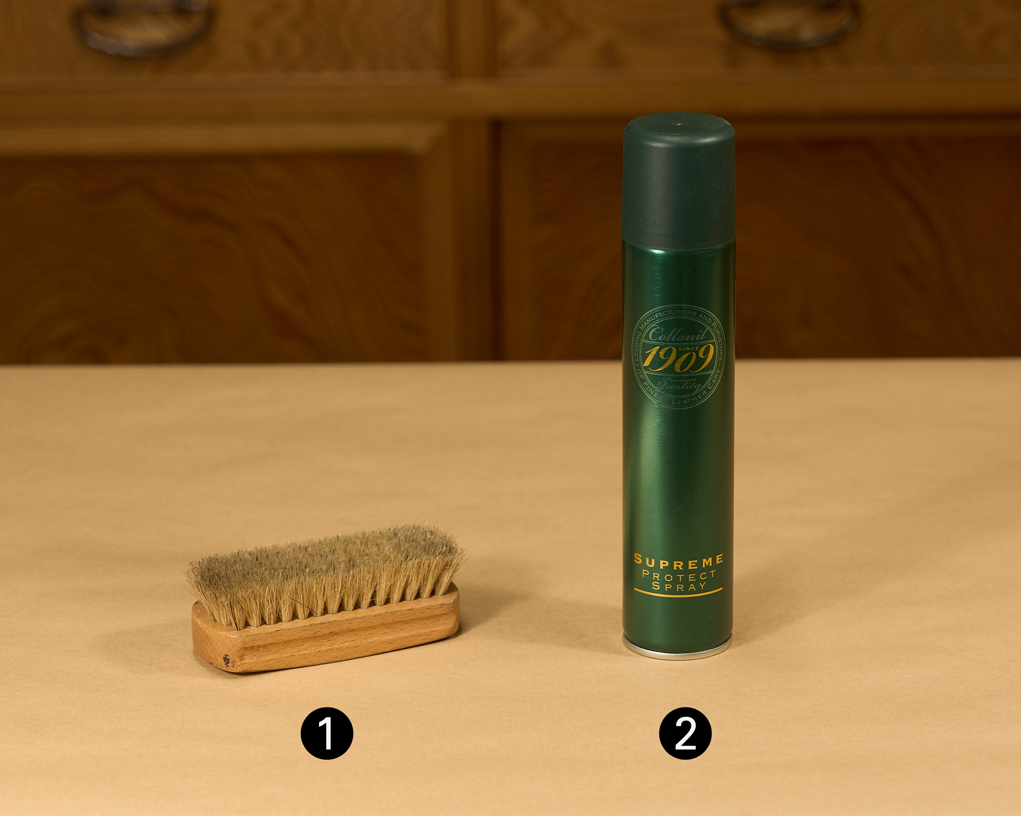 A pig bristle brush and a can of suede protector spray on a wooden surface