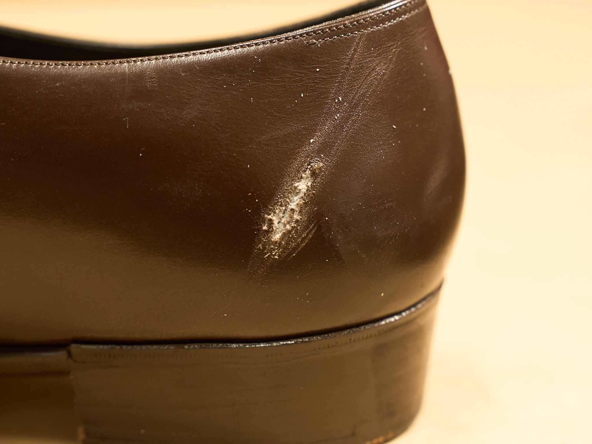 Worn brown leather shoe heel with a deep scratch